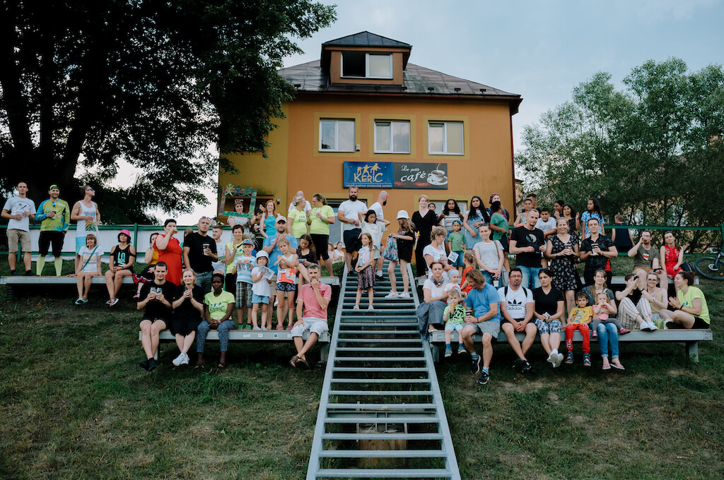People of all ages sitting on benches in front of the KERIC building in Cadca