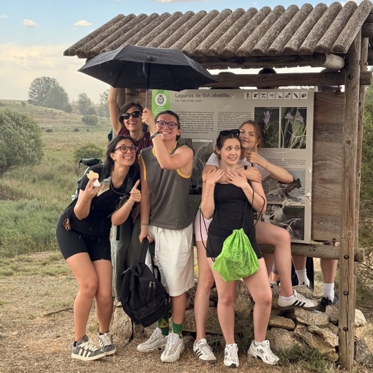 Youth exchange participants posing under an umbrella at Lagunas de Valcabadillo in Tubilla del Lago, Spain